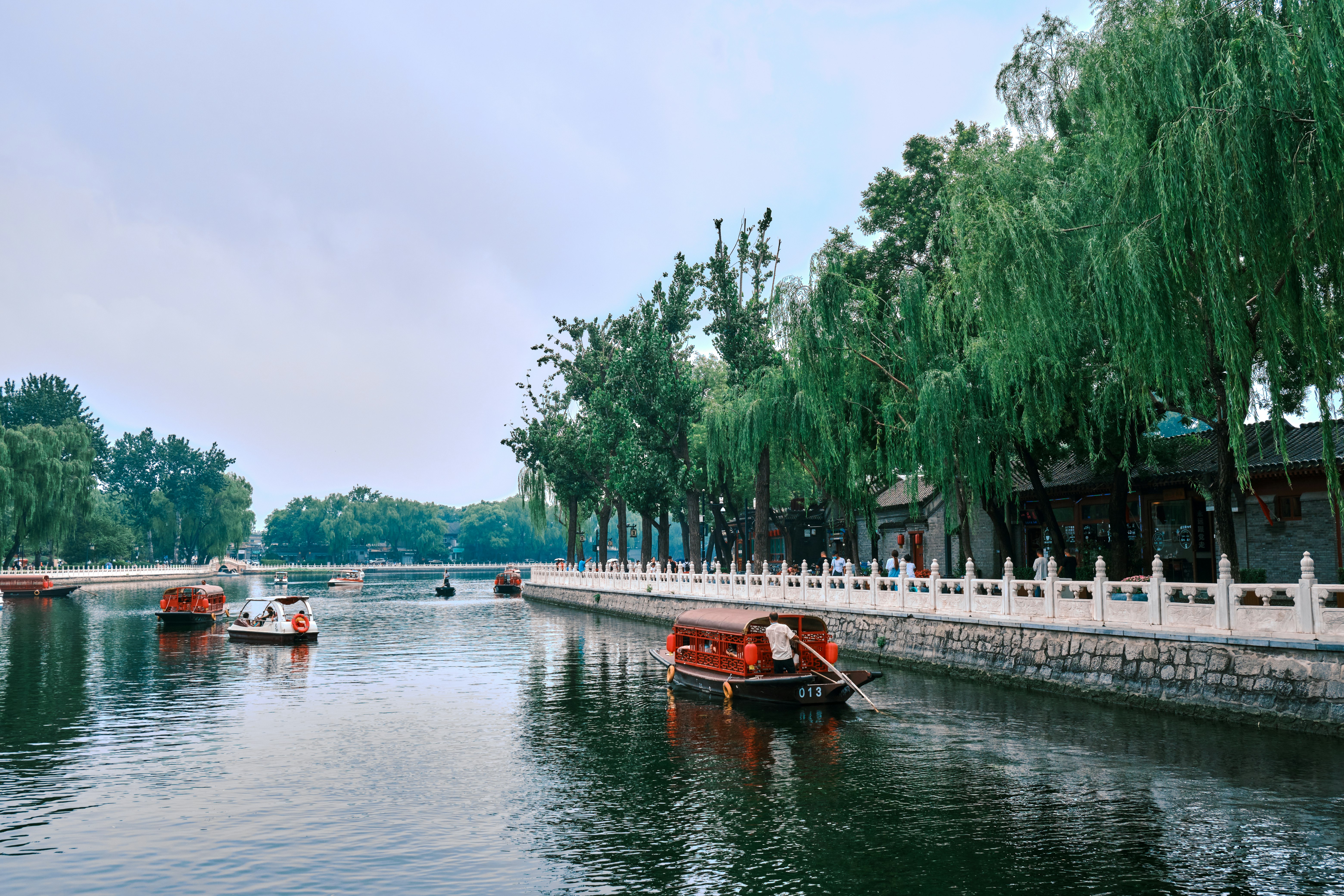 red boat on river near green trees during daytime